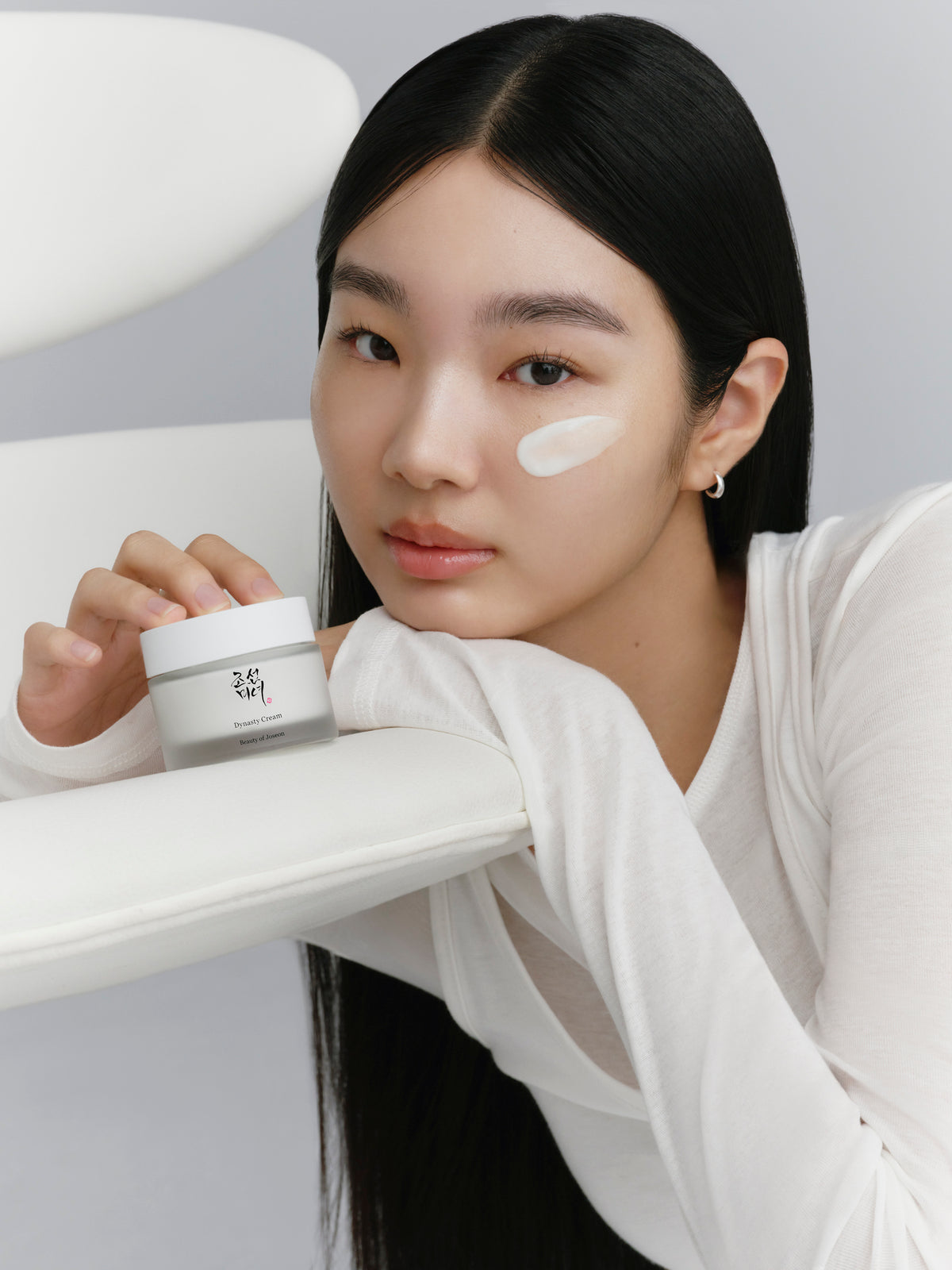 a woman holding a cream on her face