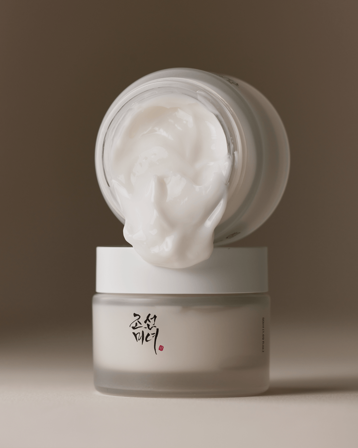 a white jar with a white cream on top of it