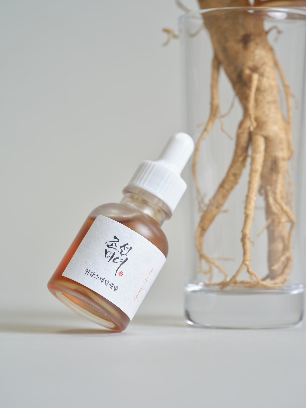 a bottle of liquid next to a glass of root